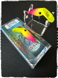 Wellen-Mo Wobbler: neon-gelber Körper mit pinkem Kopf, zwei Drillinge im Display