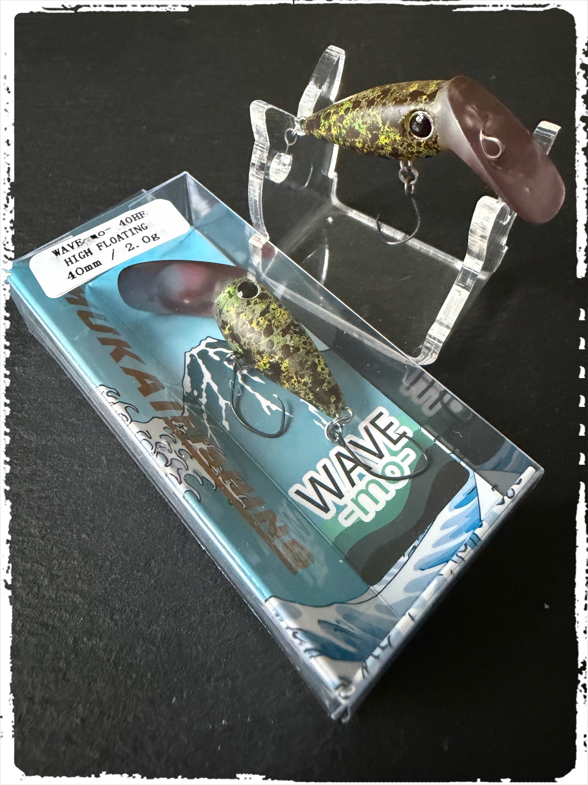 Angelköder Wave-Mo in brauner Optik mit goldenen Punkten, mit Drillhaken in blauer Verpackung.