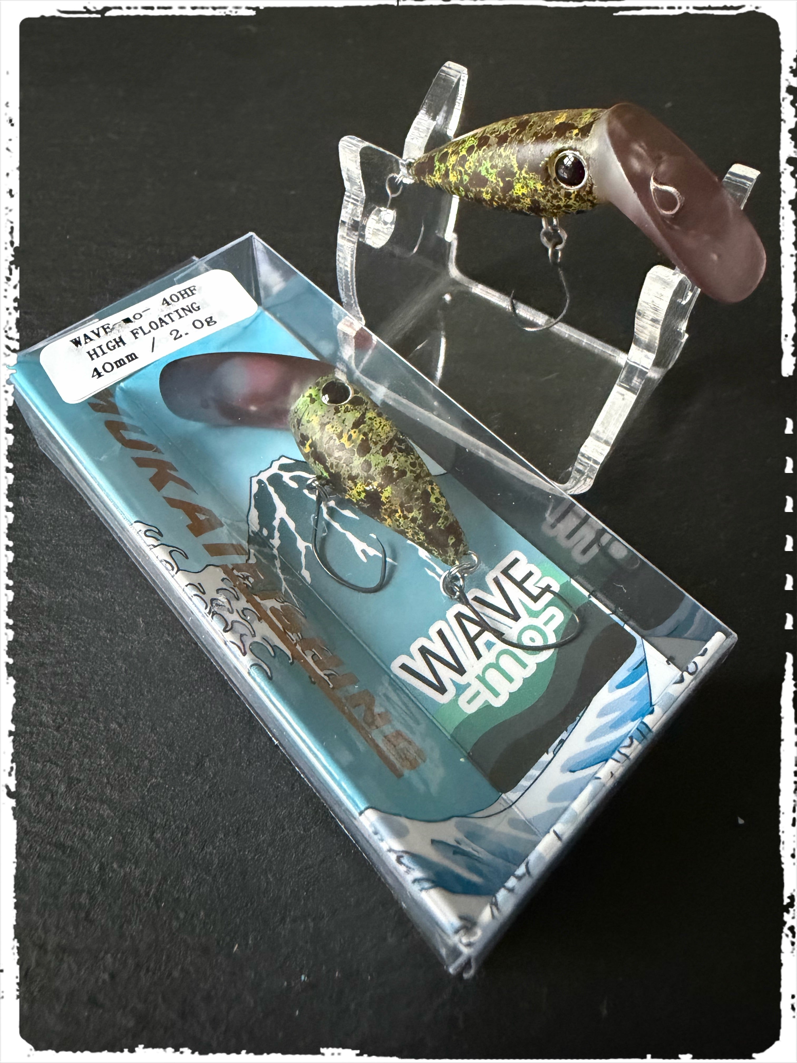 Angelköder Wave-Mo in brauner Optik mit goldenen Punkten, mit Drillhaken in blauer Verpackung.