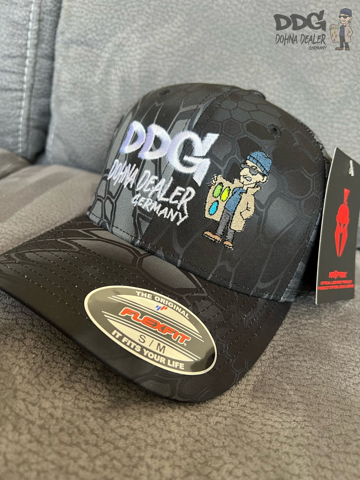 Schwarze Baseballcap mit DDG-Logo, grauem Muster und Patch am Frontschild